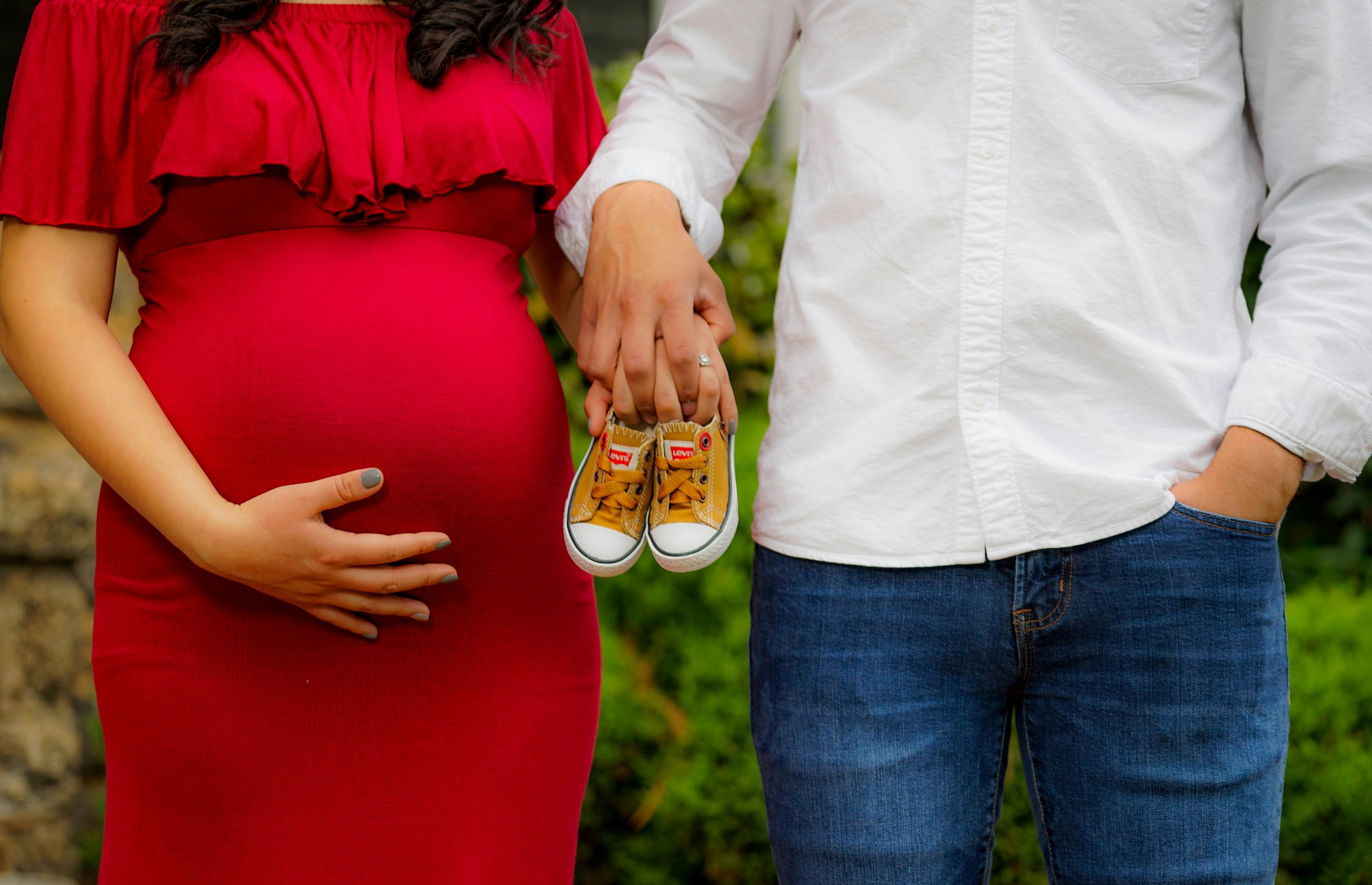 Couple expecting a baby holding tiny shoes during an outdoor maternity photo session at a natural venue near Mansfield, Ohio